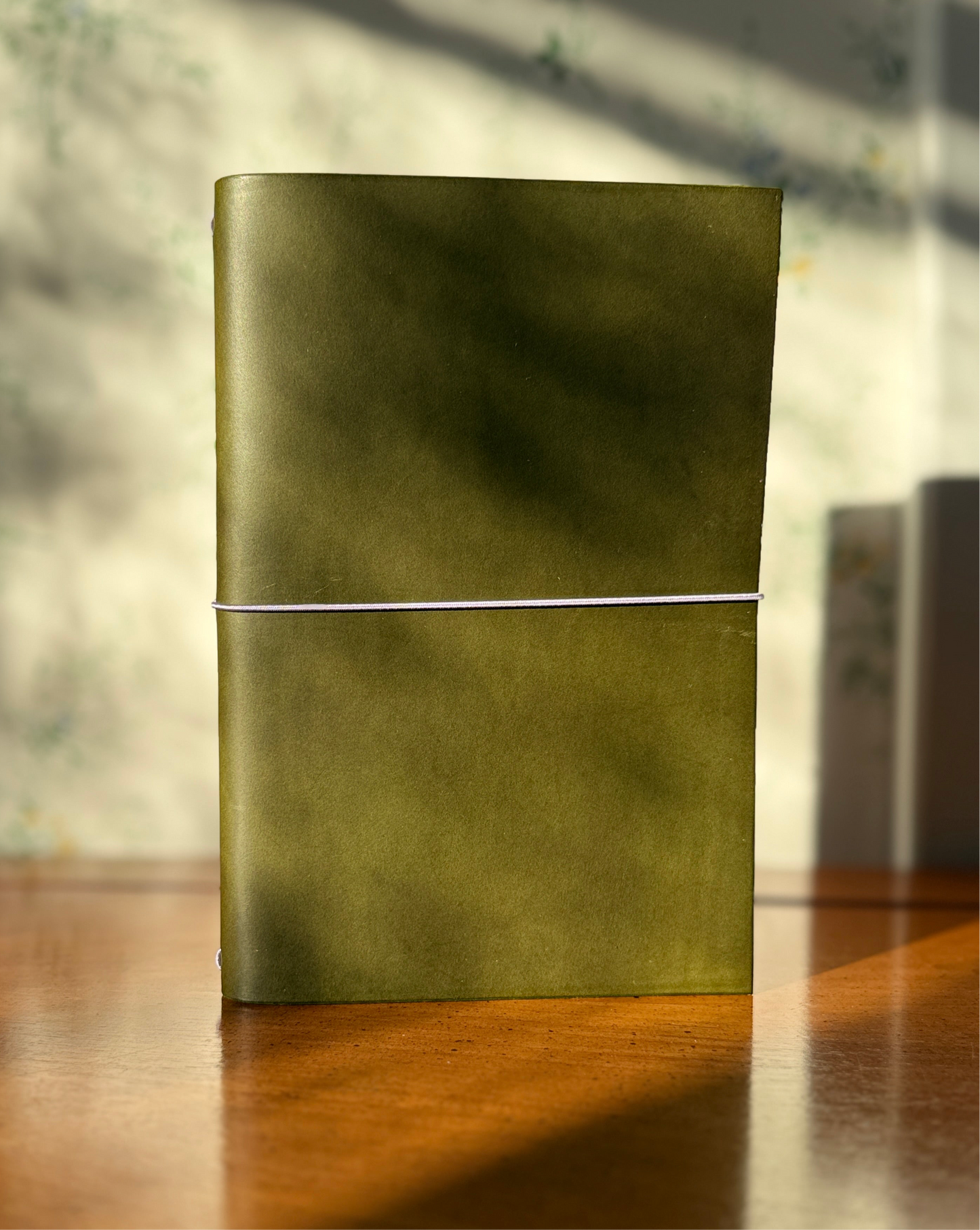 Green leather notebook on a wooden surface with a blurred background