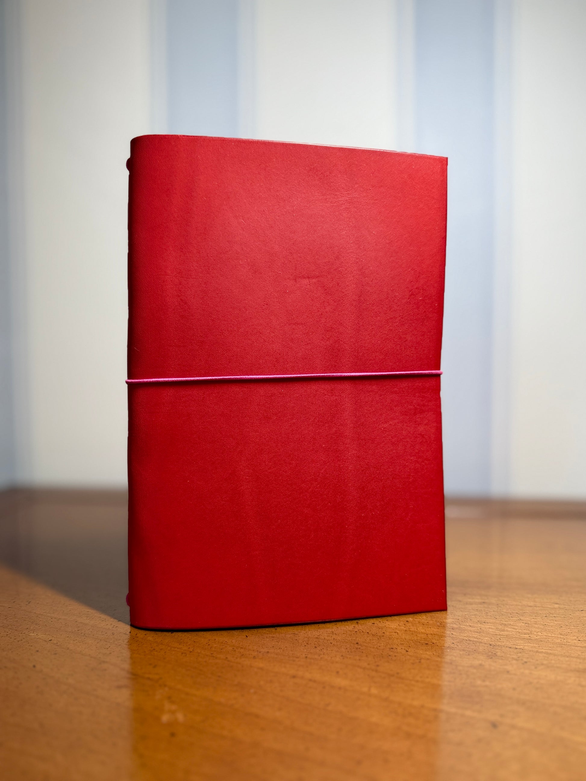 Red notebook on a wooden surface with a light gray background