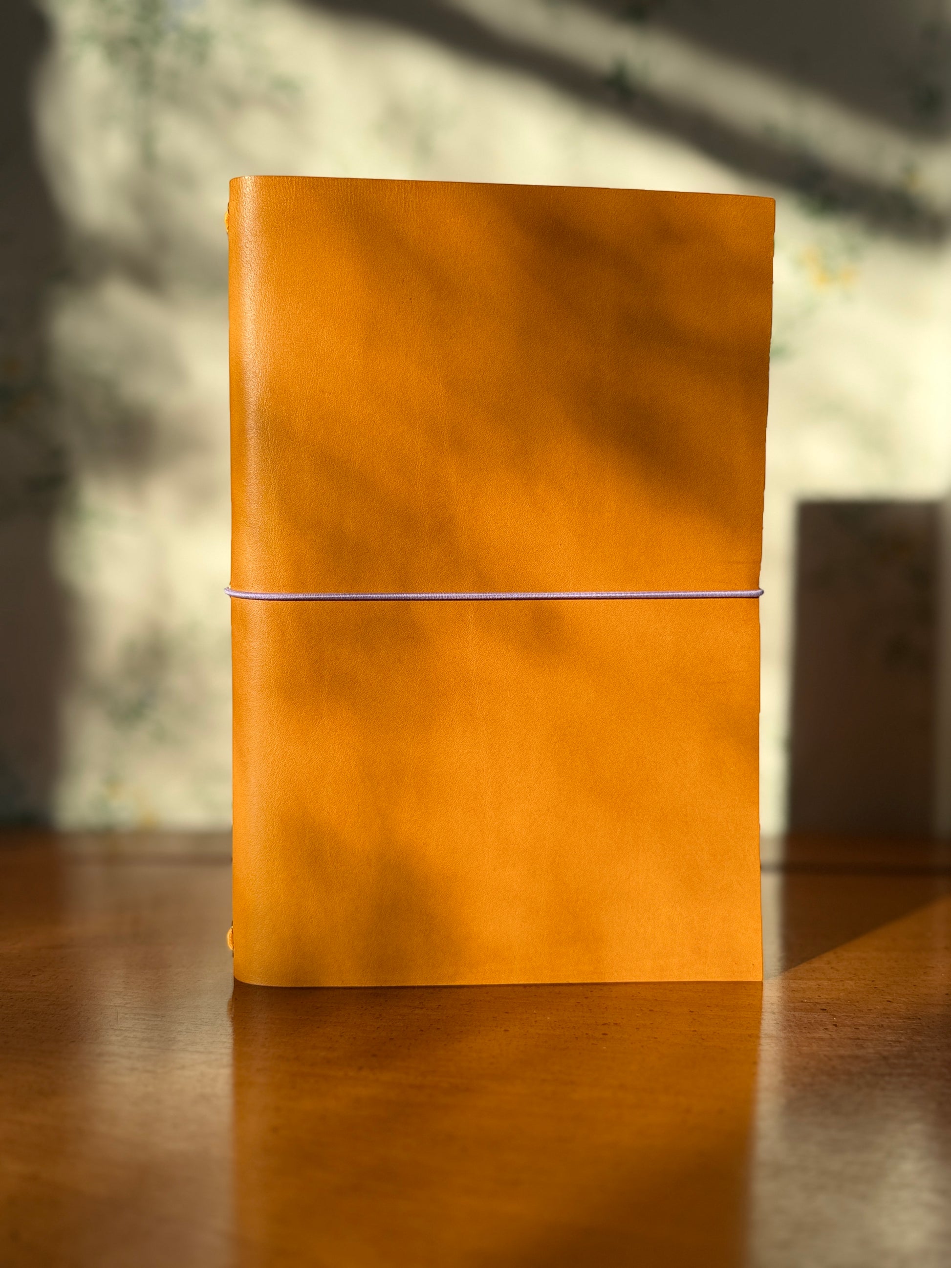 Yellow-brown leather notebook on a wooden surface with a blurred background